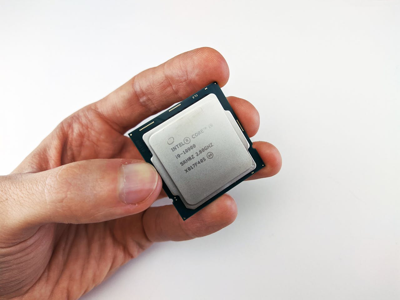 Close-up view of a hand holding an Intel Core i9 processor chip, showcasing technology details.